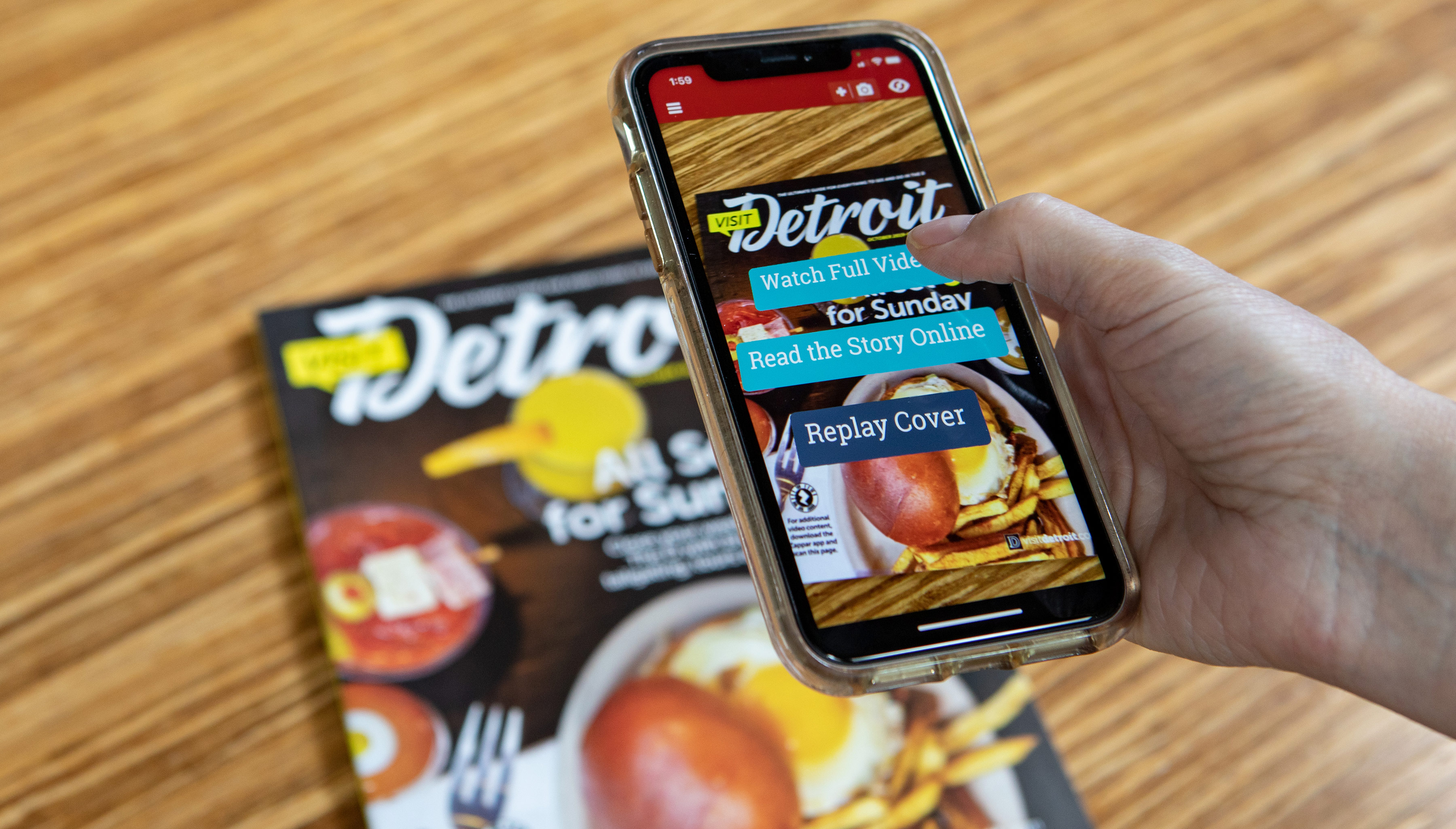 Person with Mobile phone scans the Visit Detroit Magazine Cover with augmented reality