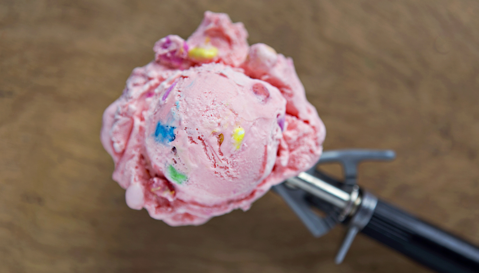 Hudsonville pink ice cream with multi-colored chunks in a scoop