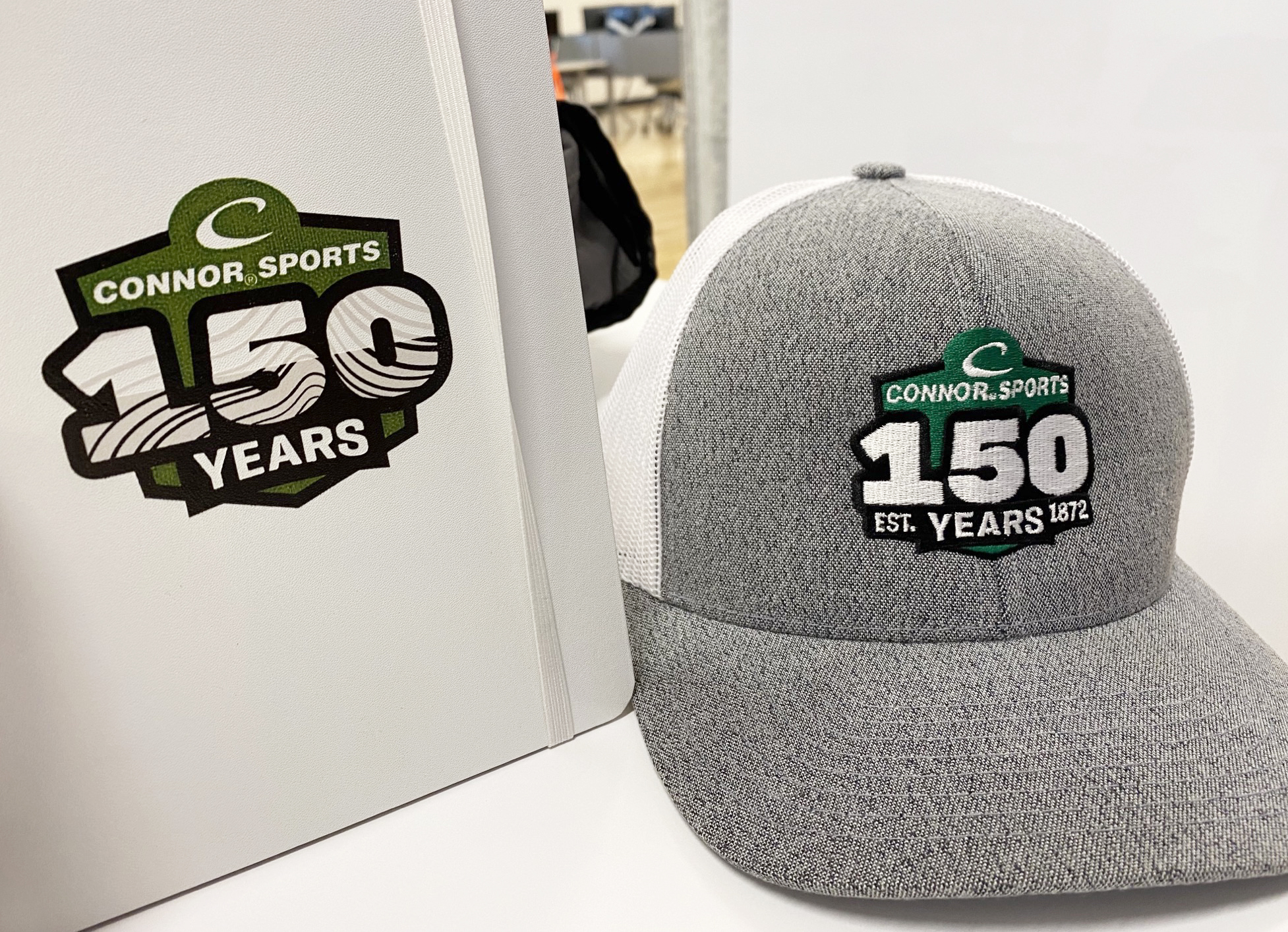 Connor Sports Anniversary logo on a binder and hat